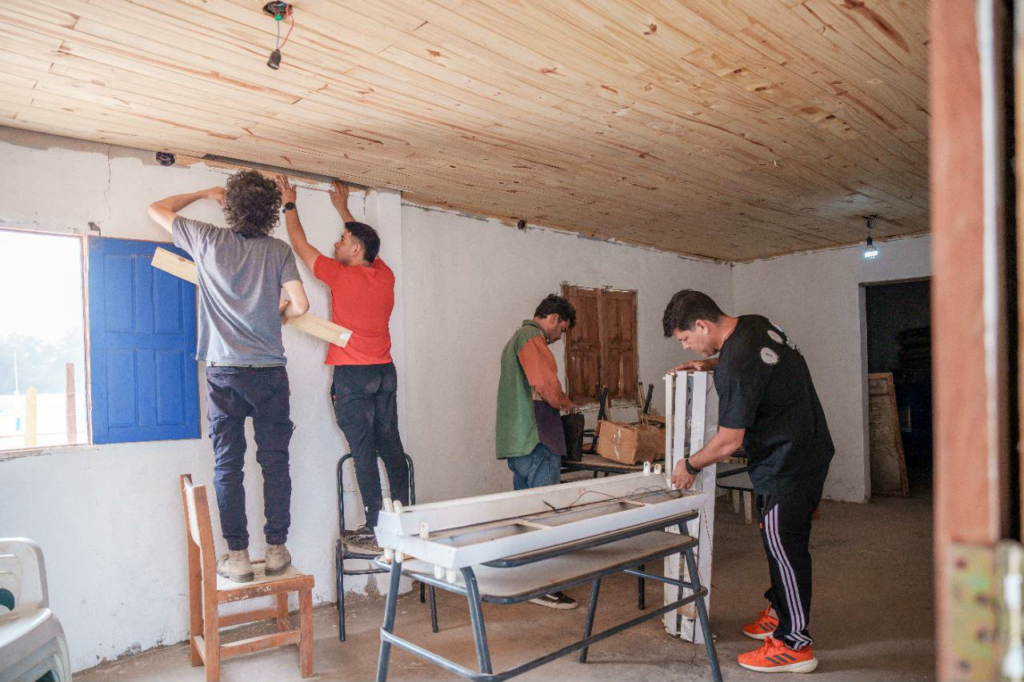 Voluntarios trabajando en la refacción interior del albergue de Tres Pozos: colocación de cielorraso de madera y armado de aberturas