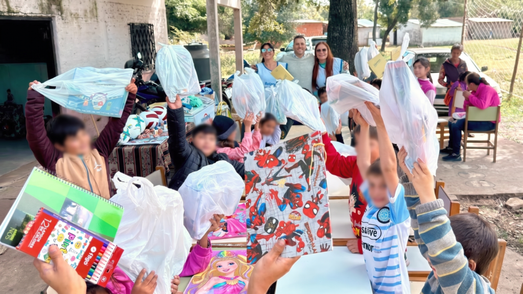 Chicos de la Escuela N.º 797 de Isla Soto levantando las bolsas de útiles escolares entregadas por Rotary Club Resistencia